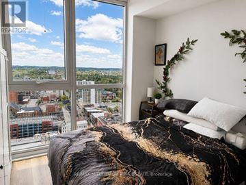 Kitchener condo for rent - A bedroom with a large bed and a view of the city.