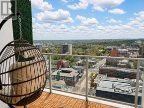 Kitchener condo for rent - A birdcage is hanging from a chain on a balcony overlooking a cityscape.