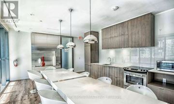 Toronto (Church-Yonge Corridor) condo for rent - A modern kitchen with a long white table and a stainless steel oven.