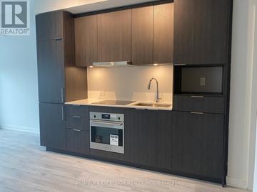 Toronto (Willowdale East) condo for rent - A modern kitchen with dark wood cabinets and stainless steel appliances.