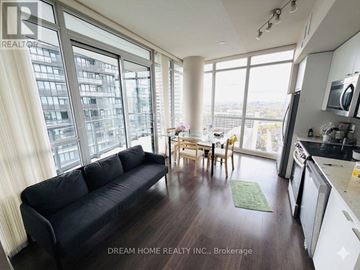 Toronto (Mount Pleasant West) condo for rent - A black couch sits in a bright living room with a dining table and chairs in the background.
