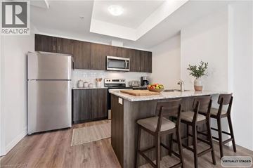 Kitchener condo for rent - A modern kitchen with a refrigerator, microwave, and bar stools.