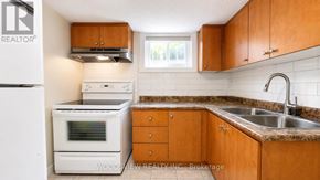 Toronto (Thistletown-Beaumonde Heights) apartment for rent - A kitchen with wooden cabinets and a white fridge.