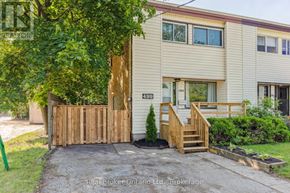 Kitchener apartment for rent - A beige house with a wooden fence and a small tree in front.