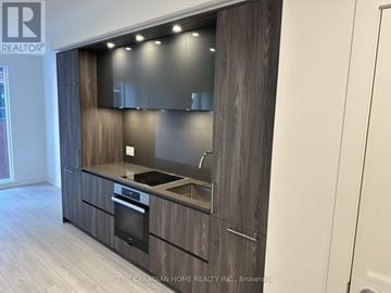 Toronto (Waterfront Communities) condo for rent - A modern kitchen with dark wood cabinets and stainless steel appliances.