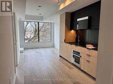 Toronto (Moss Park) condo for rent - A kitchen with wooden floors and cabinets, a microwave, and a window.