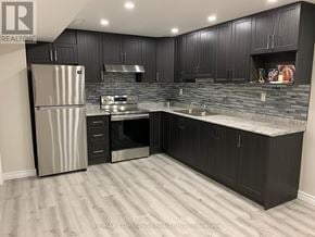 Ajax (Northeast Ajax) apartment for rent - A kitchen with black cabinets and a stainless steel refrigerator.