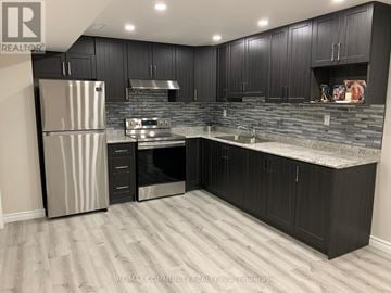 Ajax (Northeast Ajax) apartment for rent - A kitchen with black cabinets and a stainless steel refrigerator.