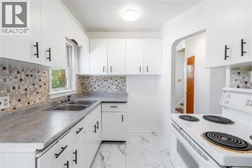 Sarnia apartment for rent - A white kitchen with a stove top oven and a sink.