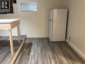 Burnaby apartment for rent - A white refrigerator sits next to a wooden table in a room with wooden flooring.