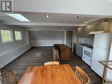 Guelph (Exhibition Park) apartment for rent - A kitchen with a table and chairs in the foreground and a window with a view of trees.