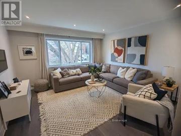 Toronto (Greenwood-Coxwell) triplex for rent - A living room with a grey sofa, a white coffee table, and a rug on the floor.