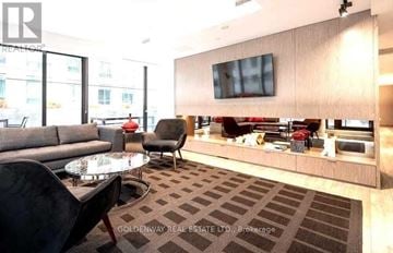 Toronto (Waterfront Communities) condo for rent - A living room with a grey couch, a black chair and a glass table.