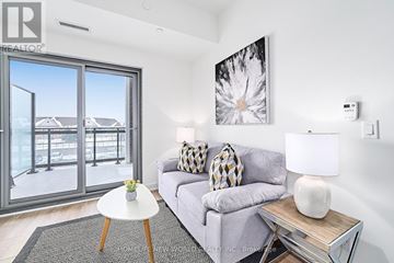 Clarington (Bowmanville) condo for rent - A living room with a grey couch, a white table, and a painting on the wall.
