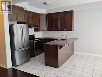 Brampton (Northwest Brampton) apartment for rent - A kitchen with brown cabinets and a black refrigerator.