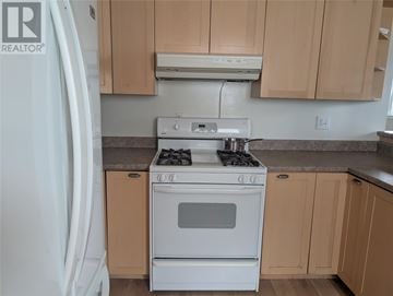 St. John's multi-family for rent - A white stove top oven with a white refrigerator in a kitchen.