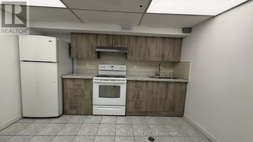 Toronto (Bayview Woods-Steeles) apartment for rent - A kitchen with a white refrigerator and wooden cabinets.