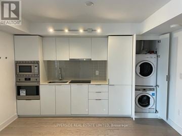 Toronto (Bay Street Corridor) condo for rent - A kitchen with white cabinets and appliances, including a microwave, oven, and dishwasher.