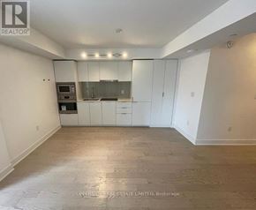 Toronto (Bay Street Corridor) condo for rent - A spacious, empty room with a kitchenette in the corner.