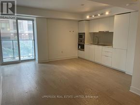 Toronto (Bay Street Corridor) condo for rent - A spacious, empty room with white cabinets and a window overlooking a city street.