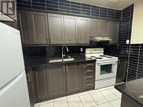 Toronto (Glenfield-Jane Heights) townhouse for rent - A kitchen with dark brown cabinets and a white stove.