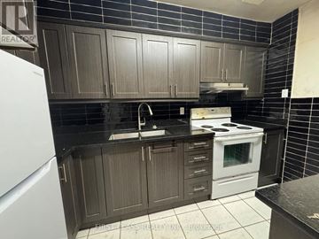 Toronto (Glenfield-Jane Heights) townhouse for rent - A kitchen with dark brown cabinets and a white stove.