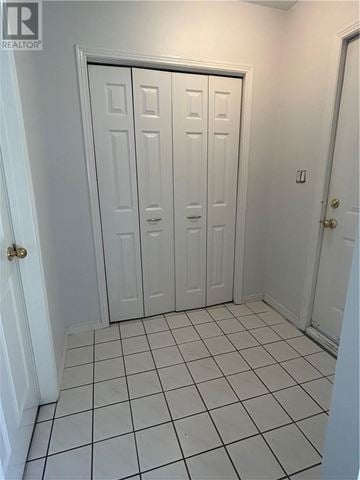 Sudbury apartment for rent - A white door with a gold handle is in a room with white walls and white tile flooring.