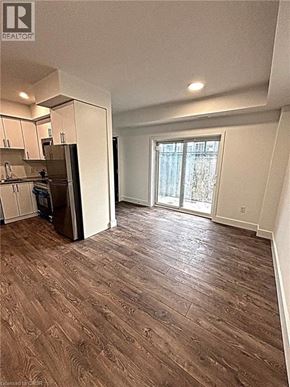 Niagara Falls townhouse for rent - A room with a wooden floor and a kitchen area with white cabinets.