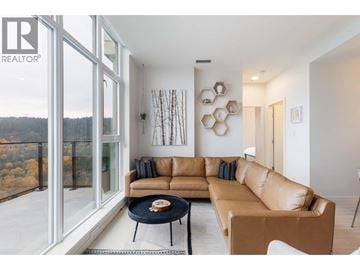 Coquitlam apartment for rent - A living room with a brown leather couch and a coffee table in front of a large window.