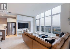 Coquitlam apartment for rent - A modern living room with a large couch and a kitchen area in the background.