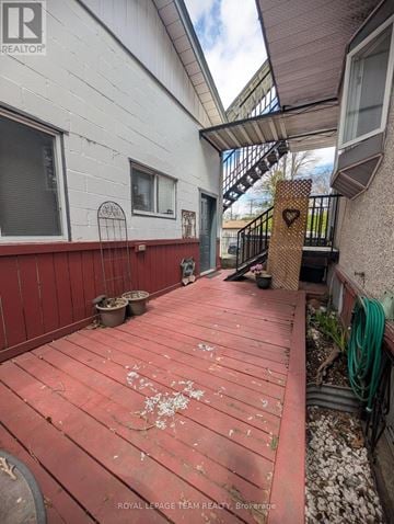 Ottawa fourplex for rent - A red wooden deck with a metal railing and a small garden area.