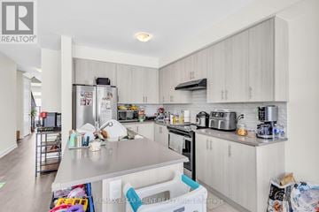 Thorold (Hurricane/Merrittville) apartment for rent - A kitchen with white cabinets and appliances, and a brokerage logo in the corner.