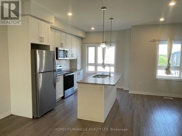 Cambridge townhouse for rent - A kitchen with a refrigerator, microwave, and oven.