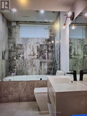 Toronto (Long Branch) apartment for rent - A bathroom with a large mirror and a bathtub.