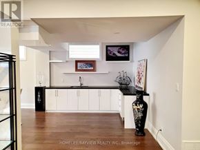 Toronto (Long Branch) apartment for rent - A black vase with flowers sits on a wooden floor in a kitchen.