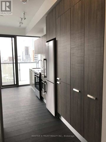Toronto (Church-Yonge Corridor) condo for rent - A kitchen with dark wood cabinets and a stainless steel refrigerator.