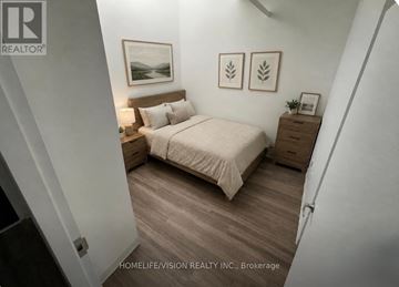Guelph (St. Patrick's Ward) condo for rent - A bedroom with a bed, nightstand, and two framed pictures on the wall.
