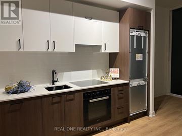 Toronto (Banbury-Don Mills) condo for rent - A kitchen with white cabinets and a black fridge.