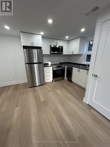 Toronto (South Riverdale) triplex for rent - A kitchen with a refrigerator, microwave, and cabinets.