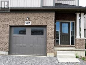 Niagara Falls (Lyons Creek) apartment for rent - A house with a grey garage door and a brick wall.