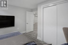 Whitchurch-Stouffville (Stouffville) apartment for rent - A bedroom with a bed, a television, and a door leading to another room.