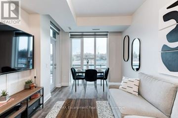 Grimsby (Grimsby Beach) condo for rent - A living room with a grey couch, a wooden table, a television, and a dining table with chairs.
