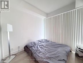 Toronto (Willowdale East) condo for rent - A bedroom with a bed, lamp, and a window with blinds.