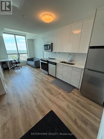 Kitchener condo for rent - A modern kitchen with wooden floors and white cabinets.