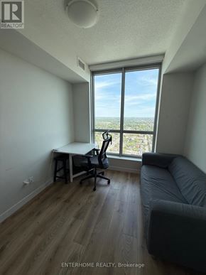 Kitchener condo for rent - A room with a desk and a couch with a window overlooking a city.
