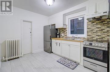 Toronto (Danforth Village-East York) apartment for rent - A kitchen with white cabinets and a stone backsplash.