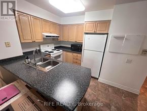 Toronto (Bay Street Corridor) condo for rent - A kitchen with a granite countertop and wooden cabinets.
