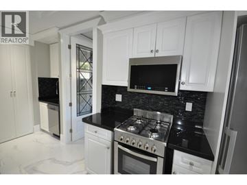 Burnaby apartment for rent - A kitchen with white cabinets and black countertops.