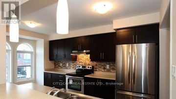 Milton (Wi Willmott) townhouse for rent - A modern kitchen with a stainless steel refrigerator and black cabinets.