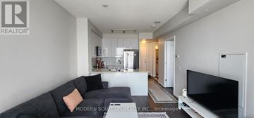 Toronto (Islington-City Centre West) condo for rent - A modern living room with a grey couch and a flat screen TV.